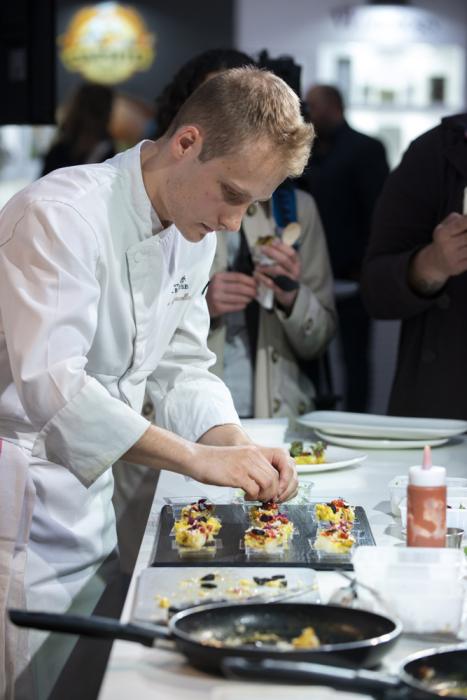 Un jeune homme applique la dernière touche finale sur son plat