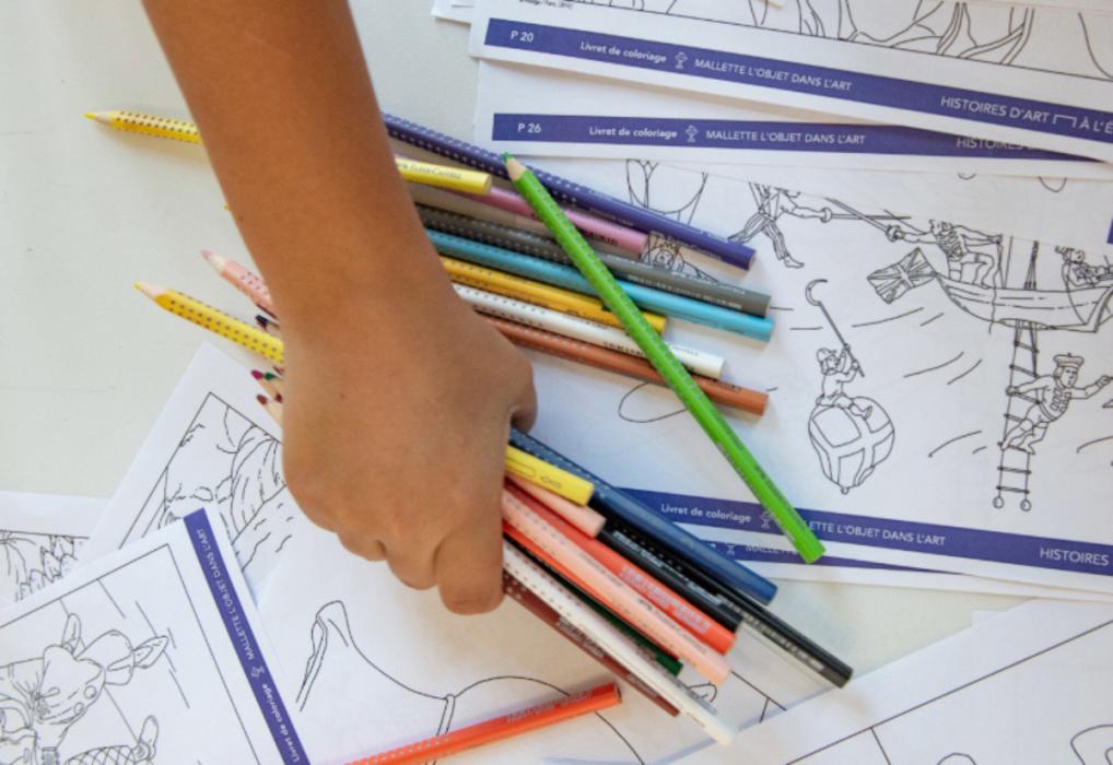 Main d'enfant avec des crayons de couleurs et un dessin