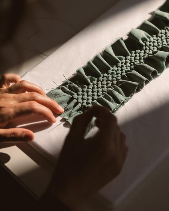 Détail de mains travaillant sur un smock canadien