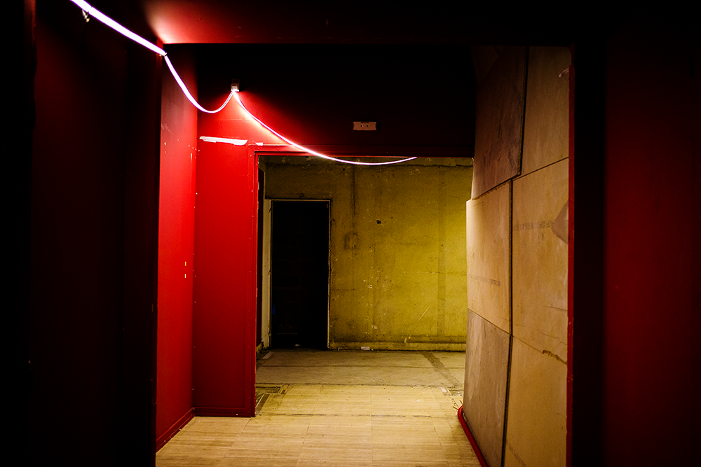 Espace du Grand Palais éclairé avec un néon, murs rouges