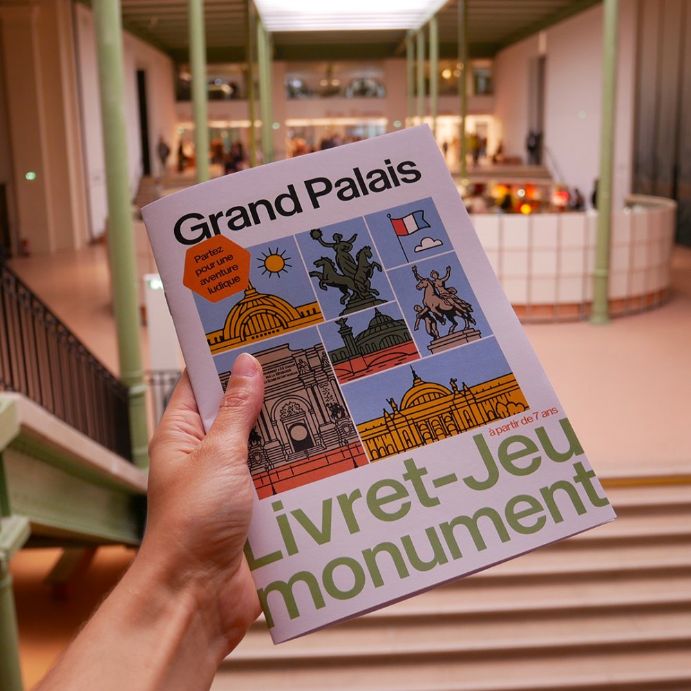 Un main tient e livret jeu, dans le Grand Palais