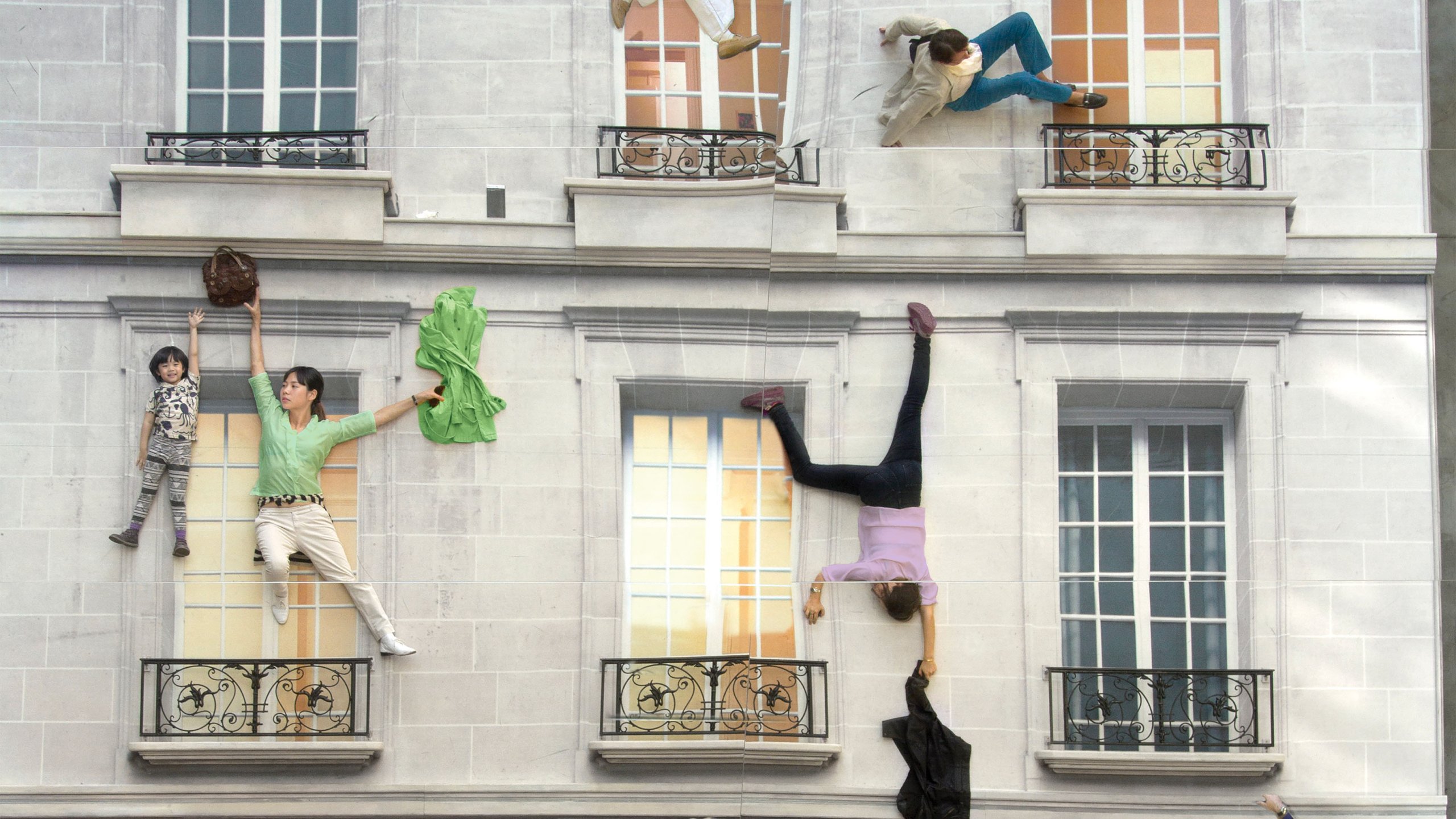 Un bâtiment de type haussmannien avec plusieurs personnes qui s'y accrochent (mise en scène)