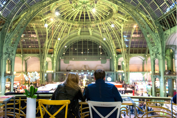 Deux personnes de dos assis à une table, dans la Nef du Grand Palais