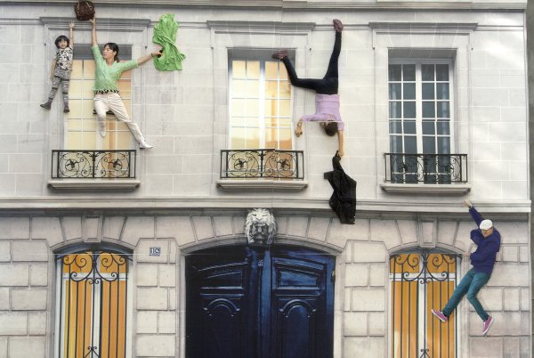 Un bâtiment de type haussmannien avec plusieurs personnes qui s'y accrochent (mise en scène)