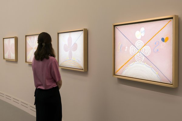 Une femme admire les tableaux d'Hilma af Klint, au Grand Palais (tons roses)