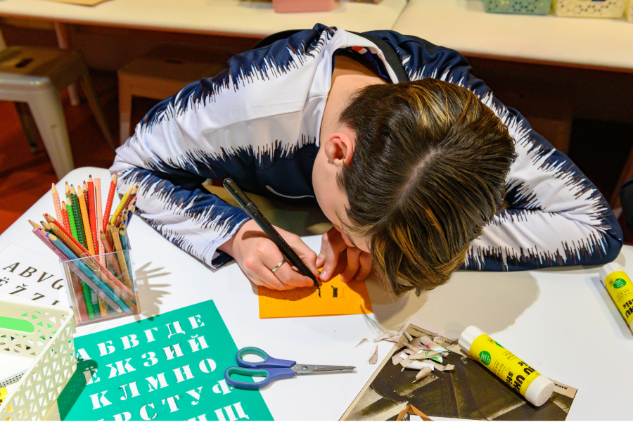 Un enfant dessine sur une feuille orange