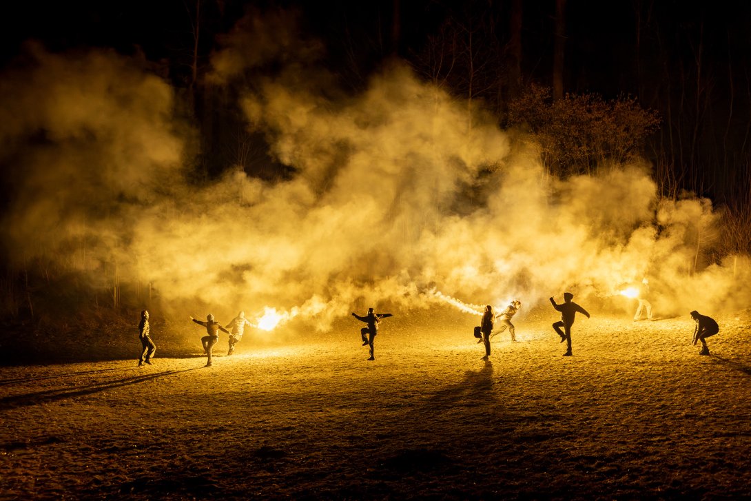 Photographie représentant des personnes avec des feux d'artifice, la nuit